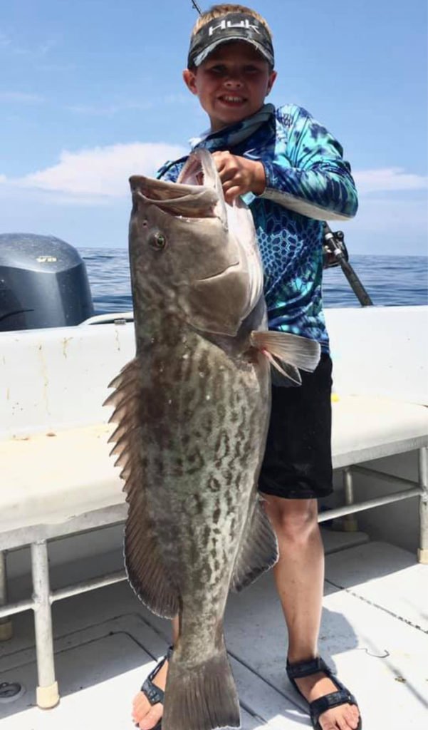Young boy holding a big grouper